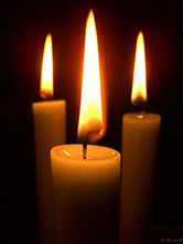 trei lumânări aprinse, în întuneric